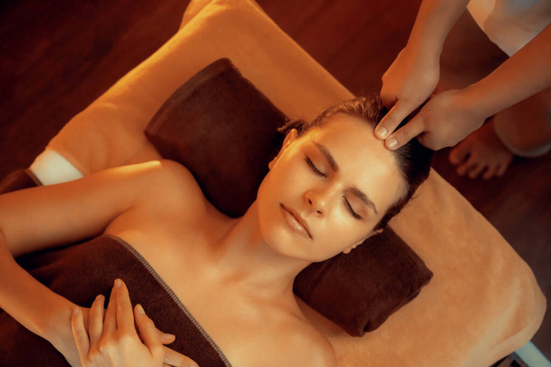 Femme caucasienne profiter relaxant anti-stress massage de la tête et choyer beauté faciale loisirs de la peau dans la bougie chaude éclairage spa salon ambiant dans un complexe de luxe ou un hôtel. Tranquillité - Photo, image