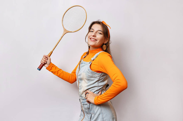 Una chica hermosa y alegre sostiene una raqueta de bádminton en su mano. - Foto, Imagen