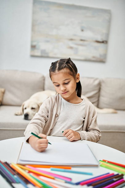 linda chica en ropa casual dibujo sobre papel con lápiz de color cerca de labrador en la sala de estar, arte - Foto, Imagen