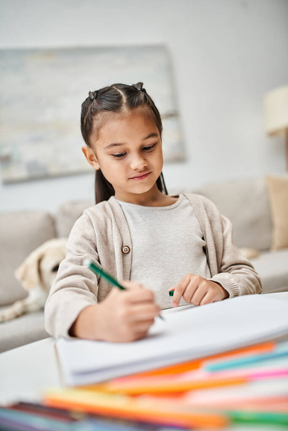 słodkie dziecko w casual ubrania rysunek na papierze z ołówkiem w pobliżu labrador w salonie, wypoczynek - Zdjęcie, obraz