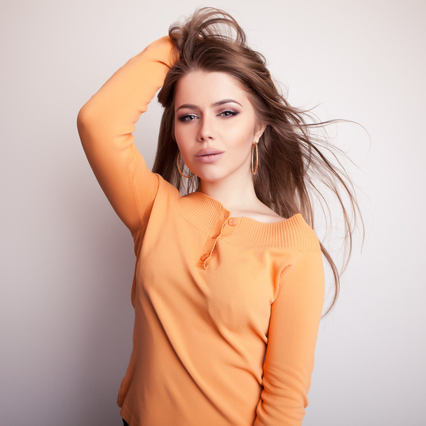 junges sinnliches Model in lässigem orangefarbenem Pullover posiert im Studio. - Foto, Bild