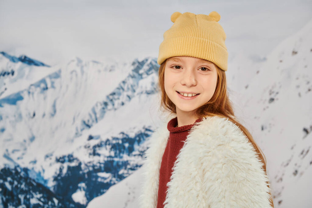 portré elegáns kislány meleg trendi ruhában mosolygós kamera hegyi háttér - Fotó, kép