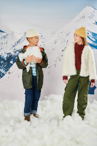 tiro vertical de amigos bonitos em roupas elegantes segurando neve e olhando um para o outro, moda - Foto, Imagem
