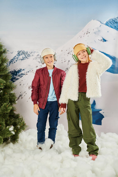 boldog gyerekek divatos ruhák headset áll a hó és mosolyogva vidáman, divat - Fotó, kép