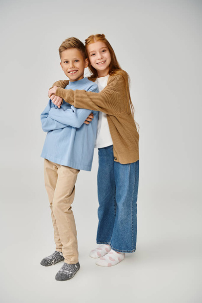 joyous little friends in casual stylish clothes hugging and smiling at camera, fashion concept - Photo, Image