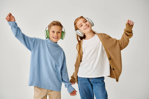 niños pequeños y alegres en ropa casual con auriculares posando en movimiento y sonriendo a la cámara - Foto, imagen