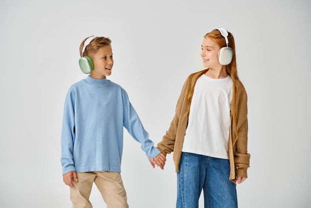 Друзья в повседневной одежде с наушниками, держащимися за руки и улыбающимися друг другу, мода - Фото, изображение