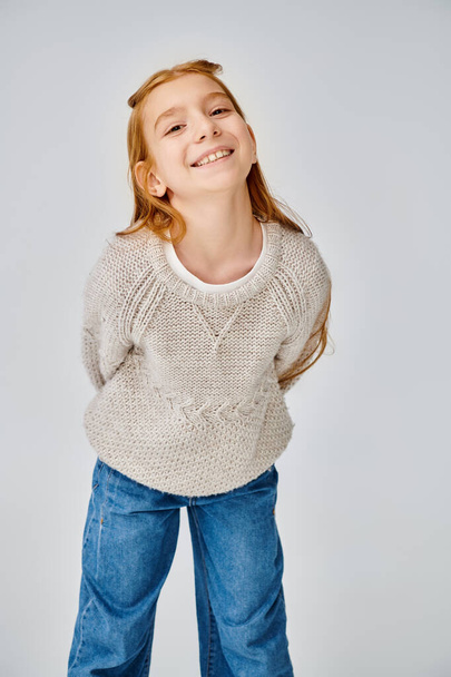 веселая девочка-подросток в трикотажном свитере радостно улыбается перед камерой, концепция моды - Фото, изображение