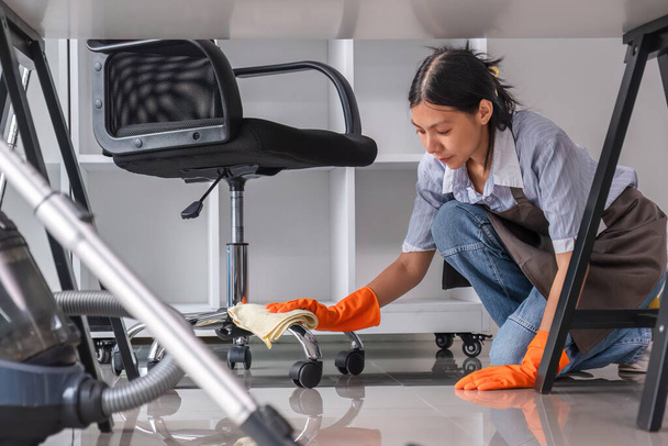 Young woman uses a cleaning cloth to disinfect the computer and equipment on the office table. Cleaning worker or housekeeper cleans the office. - Photo, Image
