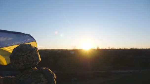 Dolly disparo de soldado del ejército ucraniano masculino levantando bandera nacional en la colina. Joven con uniforme militar ondeando la bandera de Ucrania contra el cielo azul. Victoria en la guerra. Resistencia al concepto de invasión rusa - Metraje, vídeo