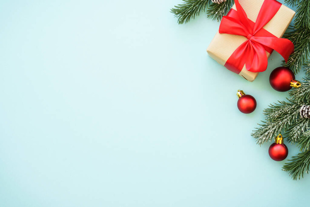 クリスマスの背景。 ブルーの背景にあるプレゼントボックスと赤の装飾. コピースペースを備えたフラットレイ画像. - 写真・画像