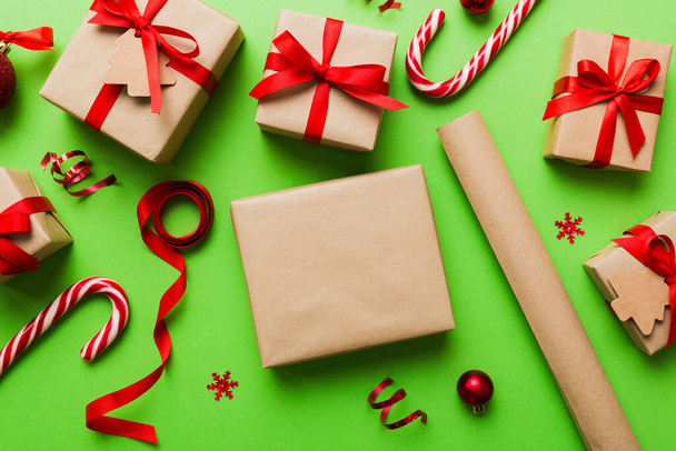 Χριστουγεννιάτικο κουτί δώρου Κραφτ με κορδέλα σε χρωματιστό φόντο. Cozy Χριστούγεννα νεκρή φύση, γενέθλια ή το νέο έτος. - Φωτογραφία, εικόνα