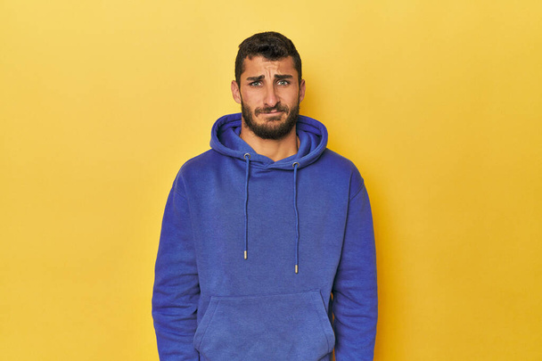 Young Hispanic man on yellow background sad, serious face, feeling miserable and displeased. - Foto, afbeelding