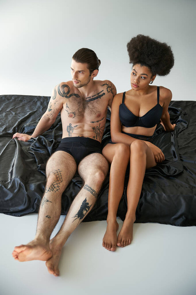 πολυπολιτισμική ελκυστικό ζευγάρι με εσώρουχα κάθεται κοντά το ένα στο άλλο στο κρεβάτι, ομαδικότητα - Φωτογραφία, εικόνα