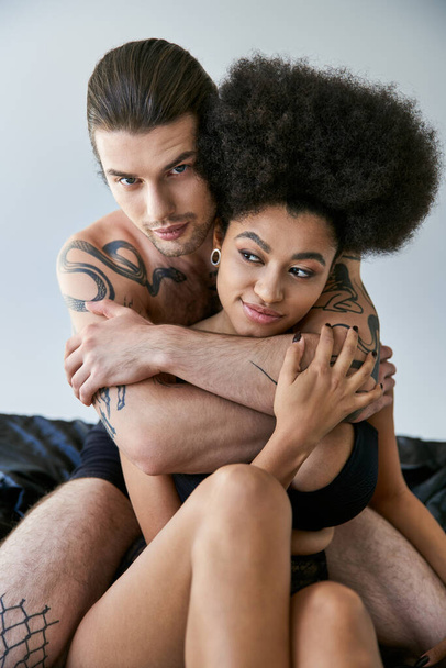 σέξι διαφυλετικό ζευγάρι με εσώρουχα που κάθονται στο κρεβάτι τους και αγκαλιάζουν με αγάπη, ομαδικότητα - Φωτογραφία, εικόνα