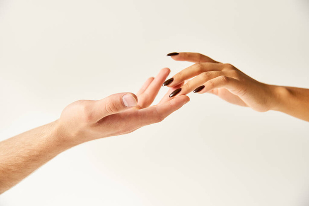 recortado vista de interracial joven pareja tocando manos y dedos de uno al otro en crudo fondo - Foto, imagen