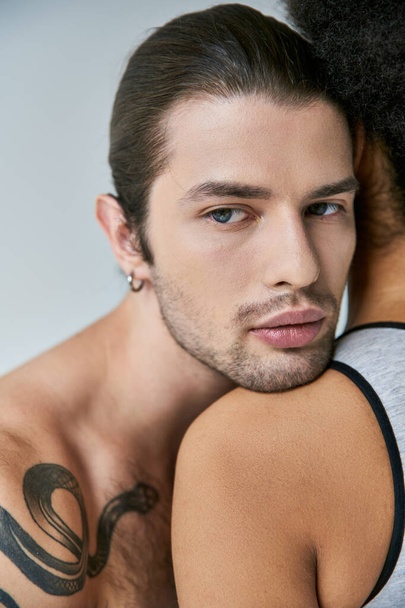 Молодой человек с хвостиком кладет голову на плечо своей африканской американской подружки, сексуальной пары - Фото, изображение