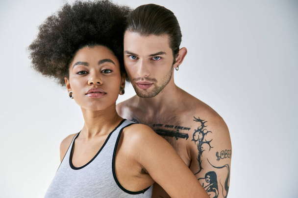 aantrekkelijk jong Afrikaans amerikaans vrouw en haar getatoeëerd vriendje knuffelen liefdevol, sexy paar - Foto, afbeelding