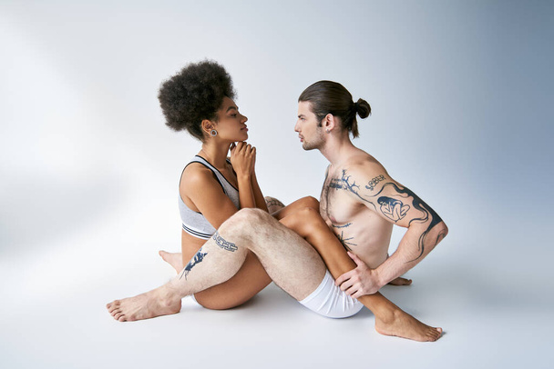όμορφο νεαρό πολυφυλετικό ζευγάρι με σέξι άνετα εσώρουχα κάθεται στο πάτωμα, ομαδικότητα - Φωτογραφία, εικόνα