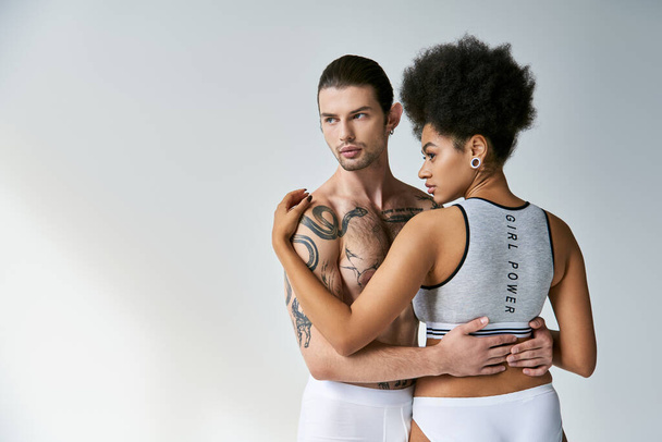 vista posterior de la atractiva mujer afroamericana abrazando a su joven novio tatuado, sexy pareja - Foto, imagen