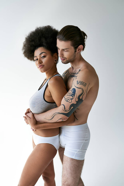 joven hombre tatuado abrazando a su hermosa novia afroamericana por detrás, sexy pareja - Foto, Imagen