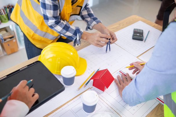 Architects and construction engineers meet to discuss blueprints of building structures in order to calculate the completion of the construction project. Real estate construction business concept. - Photo, Image