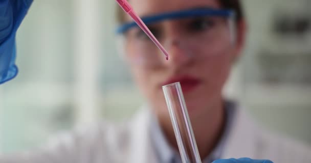 Gericht vrouwelijke wetenschapper druppelen rode vloeistof in buis met pipet in laboratorium. Het bestuderen van monsters en het uitvoeren van experiment slow motion - Video