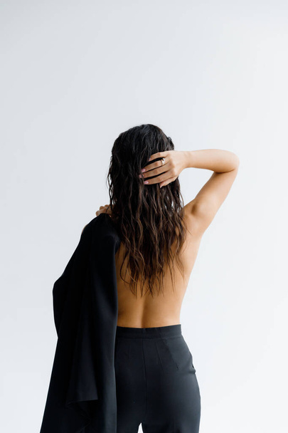 Fotoğraf stüdyosundaki lüks, seksi ve güzel bir kız siyah pantolon giyip şık bir şekilde poz veriyor. - Fotoğraf, Görsel