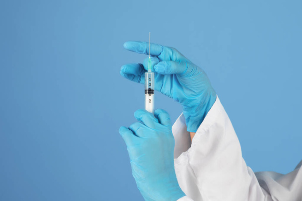Doctors Hand In Medical Latex Glove Holding Syringe With Injection Dose, Unrecognizable Doc Ready To Make Vaccination Shot, Standing Isolated On Blue Background, Closeup With Copy Space - Photo, Image