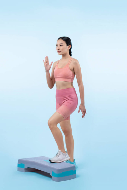 energická energická žena dělá cvičení na krátkém izolovaném pozadí studia s kardio aerobní krok cvičení. Mladý atletický asijské žena obratnost a vytrvalost trénink koncept. - Fotografie, Obrázek