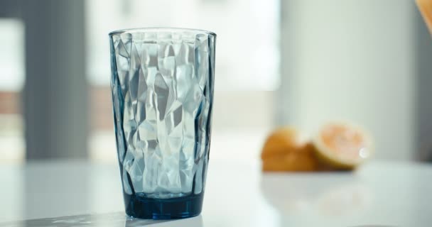 Fundo vídeo em câmera lenta de derramar uma garrafa de suco de laranja em um copo. Sumo orgânico fresco para o pequeno-almoço em casa na cozinha. Imagens 4k de alta qualidade - Filmagem, Vídeo