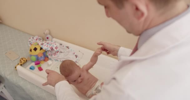 Dokter onderzoekt pasgeboren baby op kantoor, controleert zijn gezondheidstoestand.  - Video