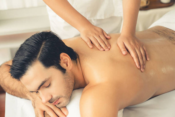 Kaukasische man klant genieten van ontspannende anti-stress spa massage en verwennerij met schoonheid huid recreatie vrijetijdsbesteding in daglicht ambient salon spa in luxe resort of hotel. Stil maar. - Foto, afbeelding