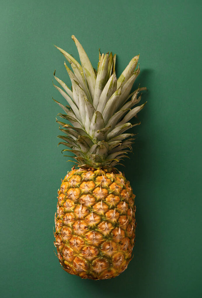 Piña jugosa madura grande entera sobre un fondo verde, fruta tropical - Foto, Imagen