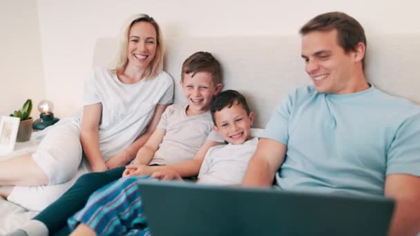 Glücklich, Laptop und Eltern mit Kindern im Bett, die sich zu Hause einen Film, eine Show oder einen Film ansehen. Lächeln, Glück und junge Mutter und Vater entspannen sich mit ihren Kindern im Schlafzimmer des modernen Familienhauses - Filmmaterial, Video
