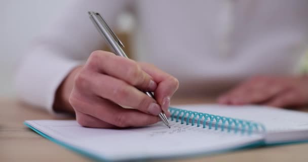 Close-up de mulher segurando caneta e criando lista de tarefas domésticas usando organizador pessoal sentado na mesa. Mulher de negócios escreve em diário e registra eventos e reuniões diariamente - Filmagem, Vídeo