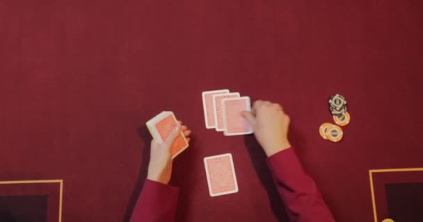 Woman playing poker on red table with chips and cards. Focus on hand - Footage, Video