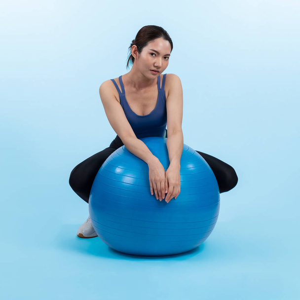 Młoda, atrakcyjna azjatycka kobieta portret w odzieży sportowej z dopasowaną piłką skierowaną na mięśnie brzucha dla skutecznego energetycznego codziennego treningu rutynowego. Zdjęcia studyjne i odizolowane tło. Energiczny - Zdjęcie, obraz