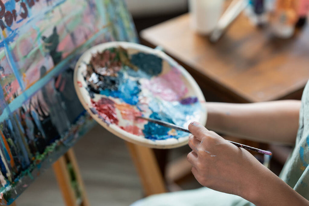 Жінка-художник тримає кольорову палітру і пензлик для малювання під час хобі майстерні. - Фото, зображення