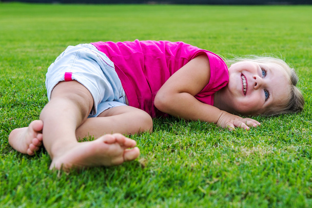 Small cute European girl posing  in the green grass. - Photo, Image