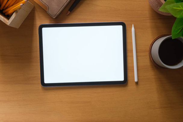Designer workspace with digital tablet, stylus pen, coffee cup and notebook on wooden table. - Photo, Image