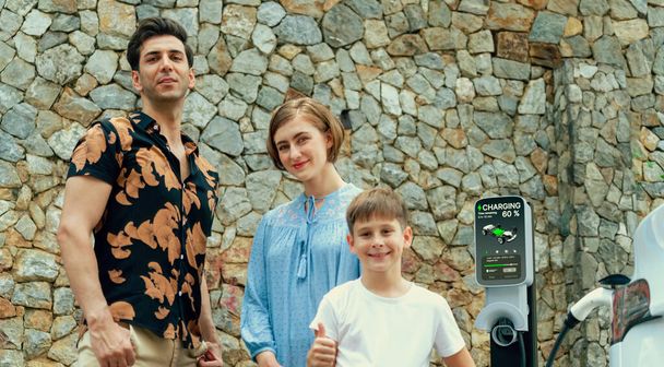 Family road trip vacation with electric vehicle, lovely family recharge EV car with green and clean energy. Stone seawall background and eco friendly car travel for sustainable environment. Perpetual - Zdjęcie, obraz