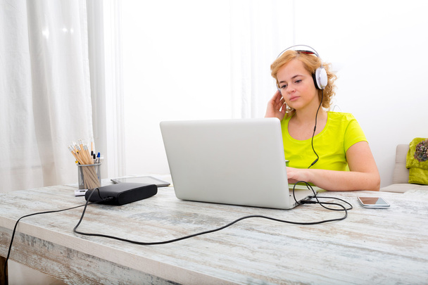 Young plus size woman listening to Audio while working on a lapt - Valokuva, kuva
