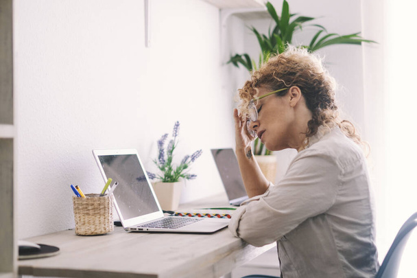 Unavená žena dotýkající se krku a brýlí před notebookem na pracovišti. Malé online podnikání počítačové technologie moderní lidé koncept životního stylu. Stres a problémy notebook podnikání - Fotografie, Obrázek