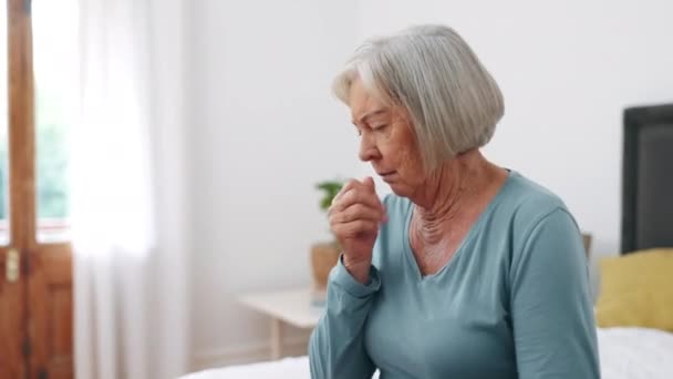 Άρρωστος, βήχας και ηλικιωμένη γυναίκα στο κρεβάτι με αλλεργίες, πονόλαιμο και λοίμωξη στο στήθος στο σπίτι. Συνταξιοδότηση, υγειονομική περίθαλψη και ηλικιωμένα άτομα στην κρεβατοκάμαρα με συμπτώματα ασθένειας, πόνου και άσθματος το πρωί. - Πλάνα, βίντεο