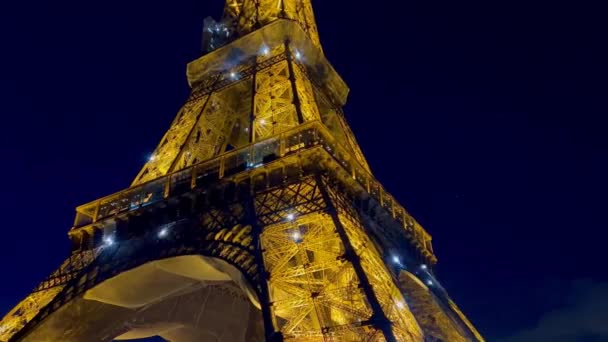 Eine Nahaufnahme des Eiffelturms, der in der Abenddämmerung in Paris glüht. Blick auf den Eiffelturm mit nächtlicher Beleuchtung. Der Eiffelturm ist das meistbesuchte Monument von Paris. Ein Pariser Traum  - Filmmaterial, Video