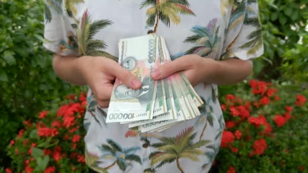 Woman in a tropical shirt holding Laotian Kip. Close up. - Footage, Video