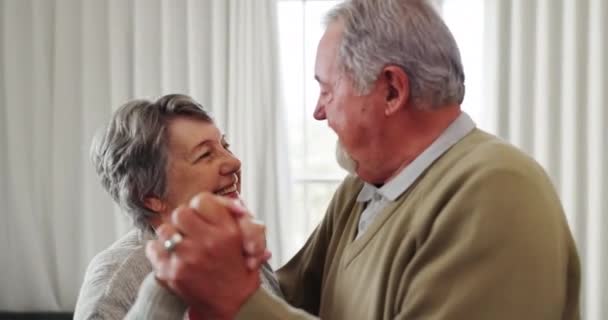 Tanz, Liebe und ein älteres Paar im Haus für verspielte Romantik im Ruhestand. Lächeln, entspannen oder lustig mit einem glücklichen älteren Mann und einer unbeschwerten Frau, die sich im Wohnzimmer zur Musik bewegen. - Filmmaterial, Video