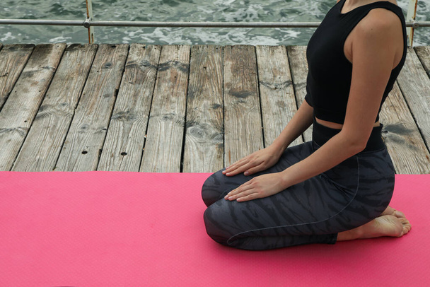 Женщина на коврике для йоги на деревянном полу у моря, место для текста - Фото, изображение