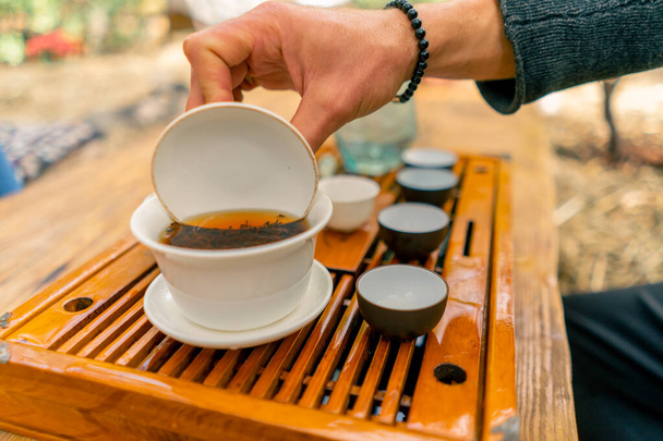 Közelkép a természetes kínai tealevelekről, amelyeket egy különleges kerámia tálban főznek fedővel az ünnepség alatt. - Fotó, kép